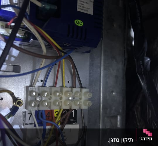 תמונת תקריב של חיבורי חשמל ולוח פיקוד במזגן במהלך עבודת תיקון